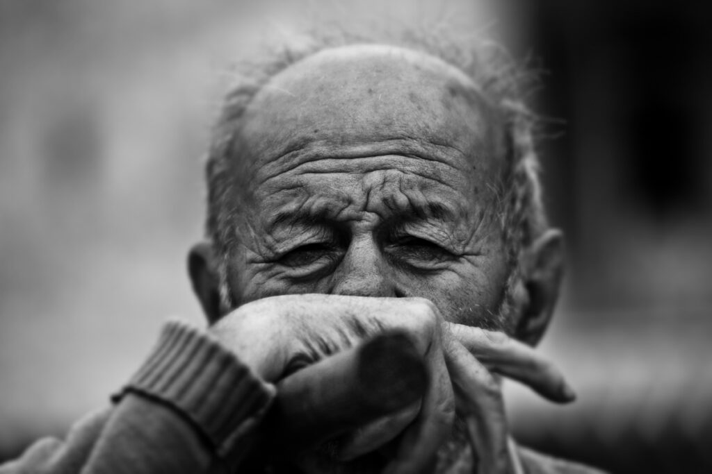 An older man with his hand in front of his face representing the emotional journey of dementia caregiving, reflection, and planning for the future.